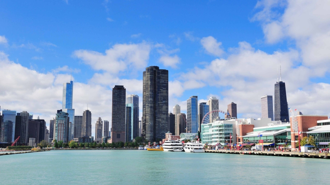 Chicago city downtown urban skyline with skyscrapers over Lake Michigan with cloudy blue sky.